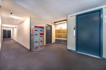 A hallway with a mailbox and a filing cabinet.